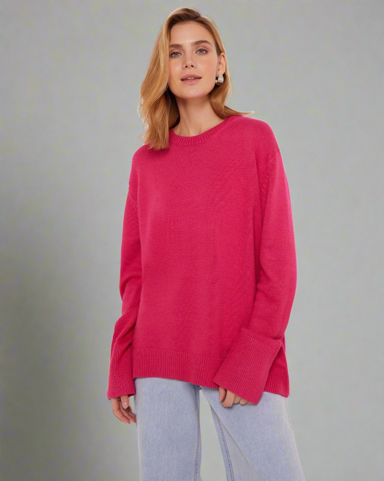 Woman wearing a coral red oversized cashmere sweater.