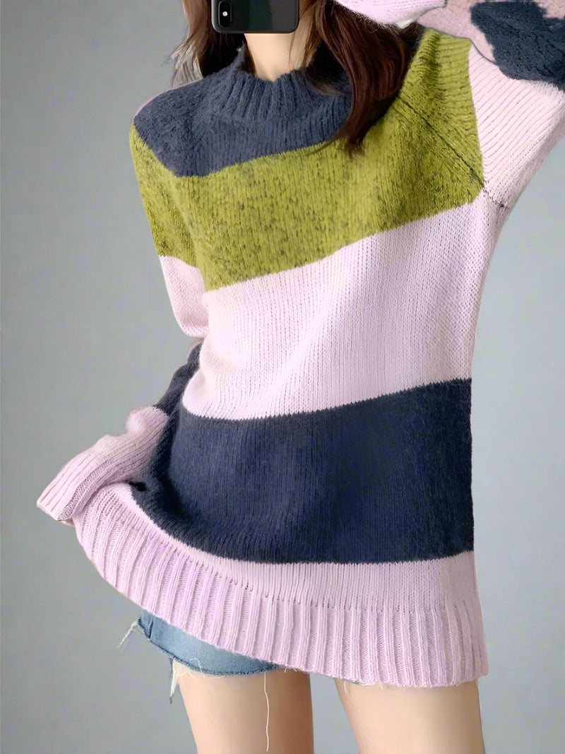 Woman wearing a colorblock knit sweater with navy, olive green, and soft pink stripes.