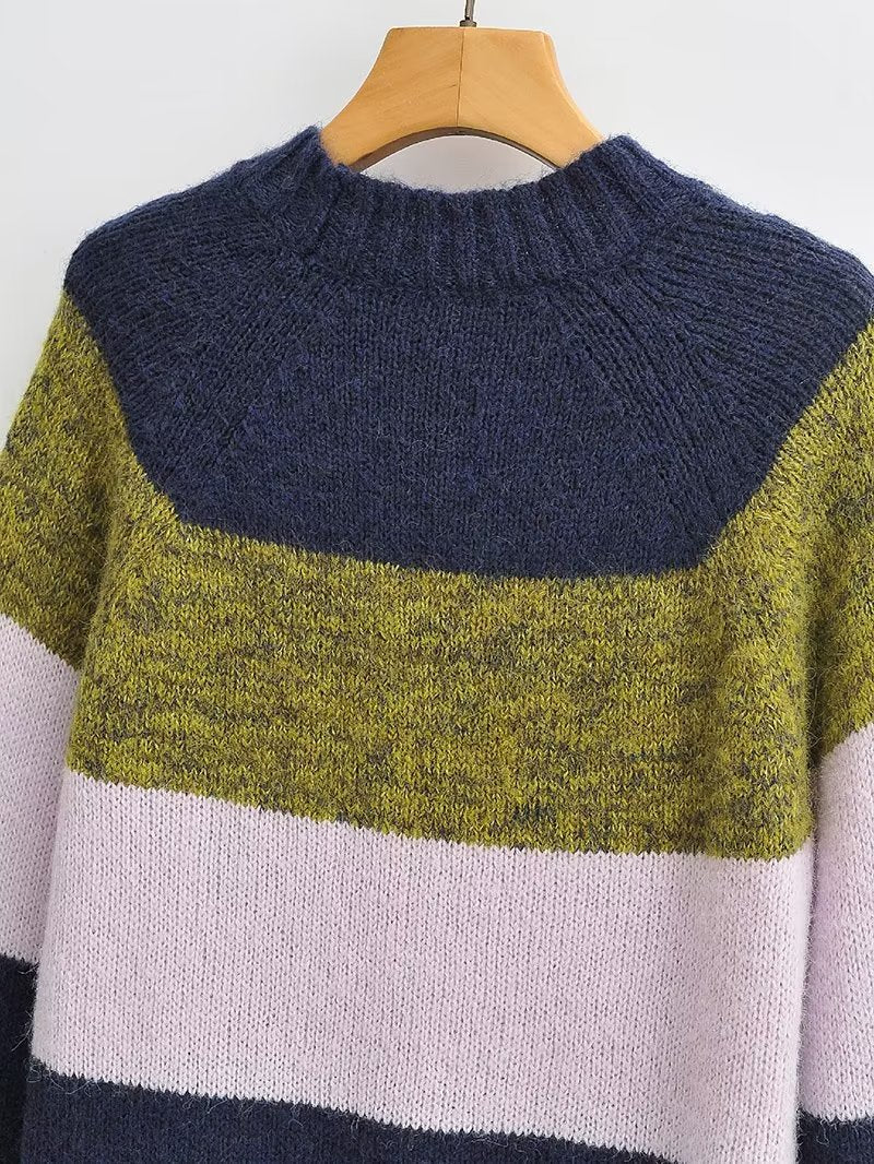 Woman wearing a colorblock knit sweater with navy, olive green, and soft pink stripes.