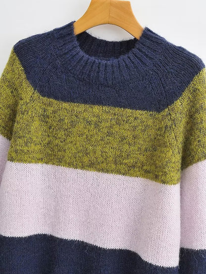 Woman wearing a colorblock knit sweater with navy, olive green, and soft pink stripes.