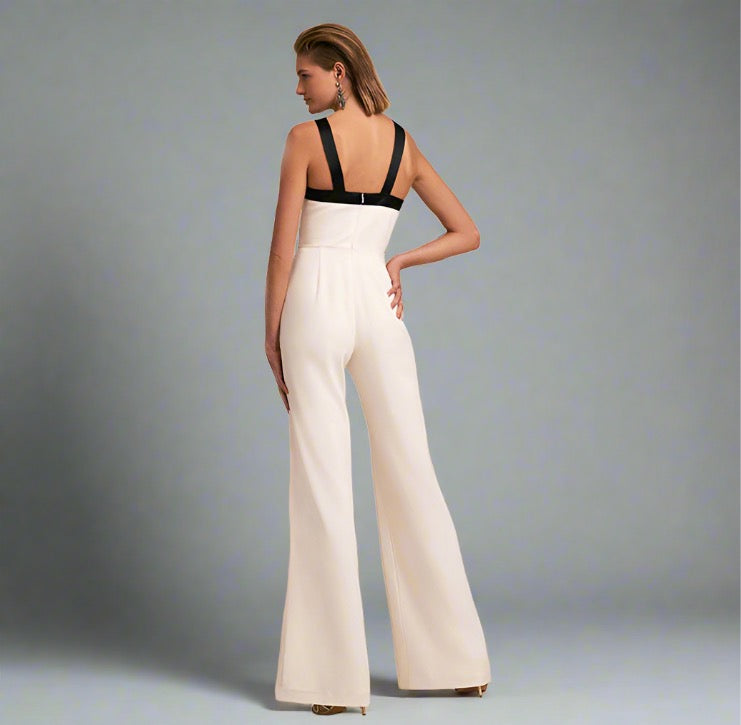 Woman wearing a white halter jumpsuit with a black bow detail and wide-leg design, ideal for elegant travel occasions.