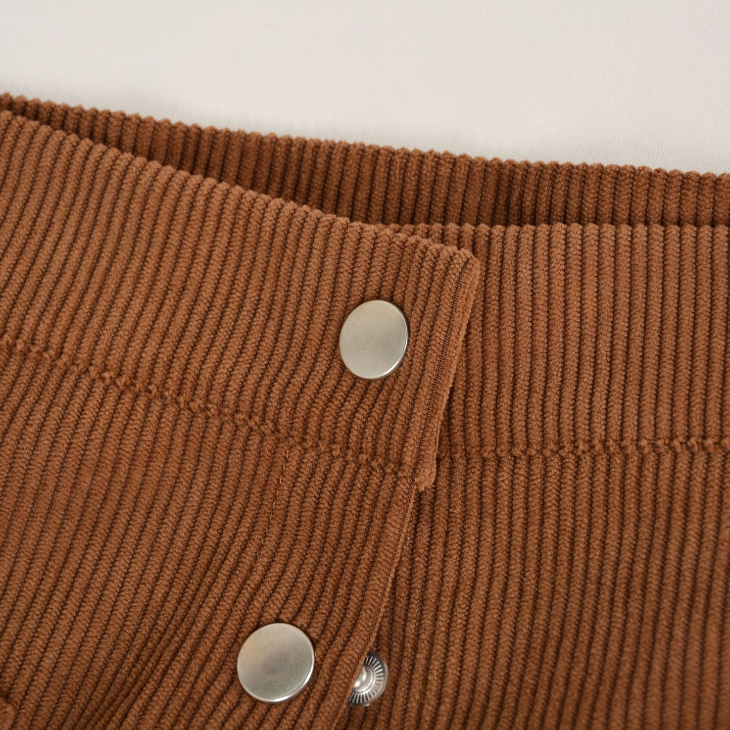 Woman wearing a High-Waist Corduroy Button-Up Skirt in a warm, earthy tone, featuring a front button-up closure and two front pockets.