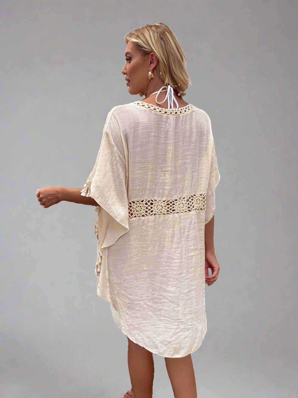 Woman wearing a boho crochet tassel cover-up in apricot.