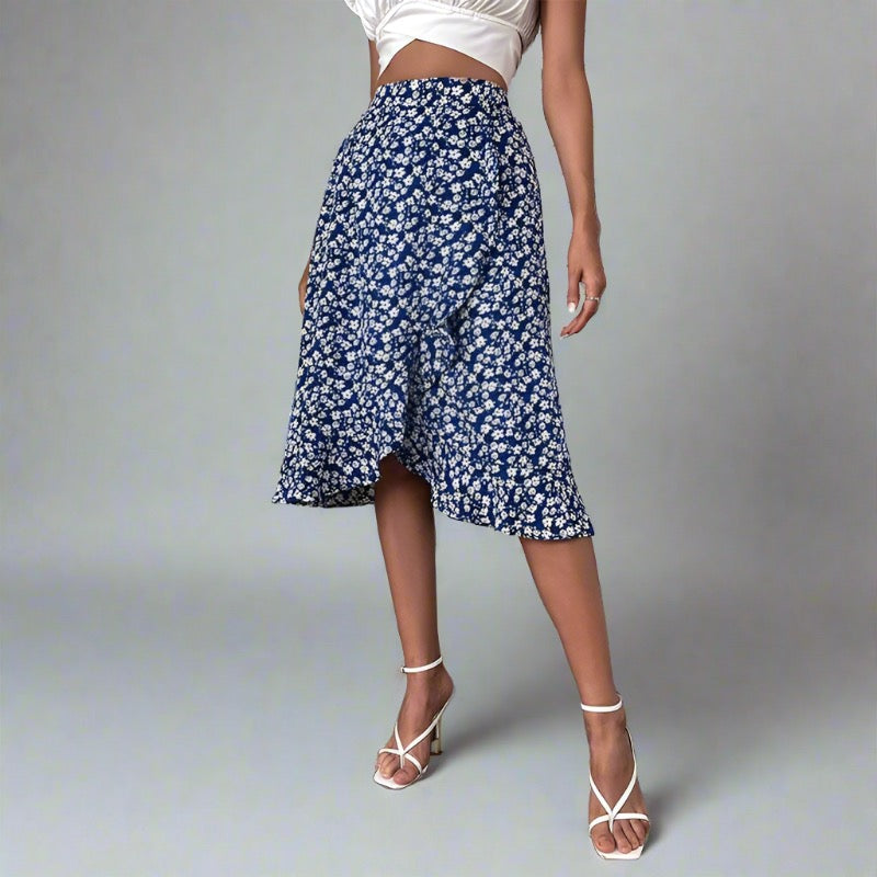 Woman wearing a blue midi skirt with a white floral print, paired with a white crop top and white strappy heels