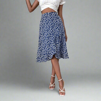 Woman wearing a blue midi skirt with a white floral print, paired with a white crop top and white strappy heels