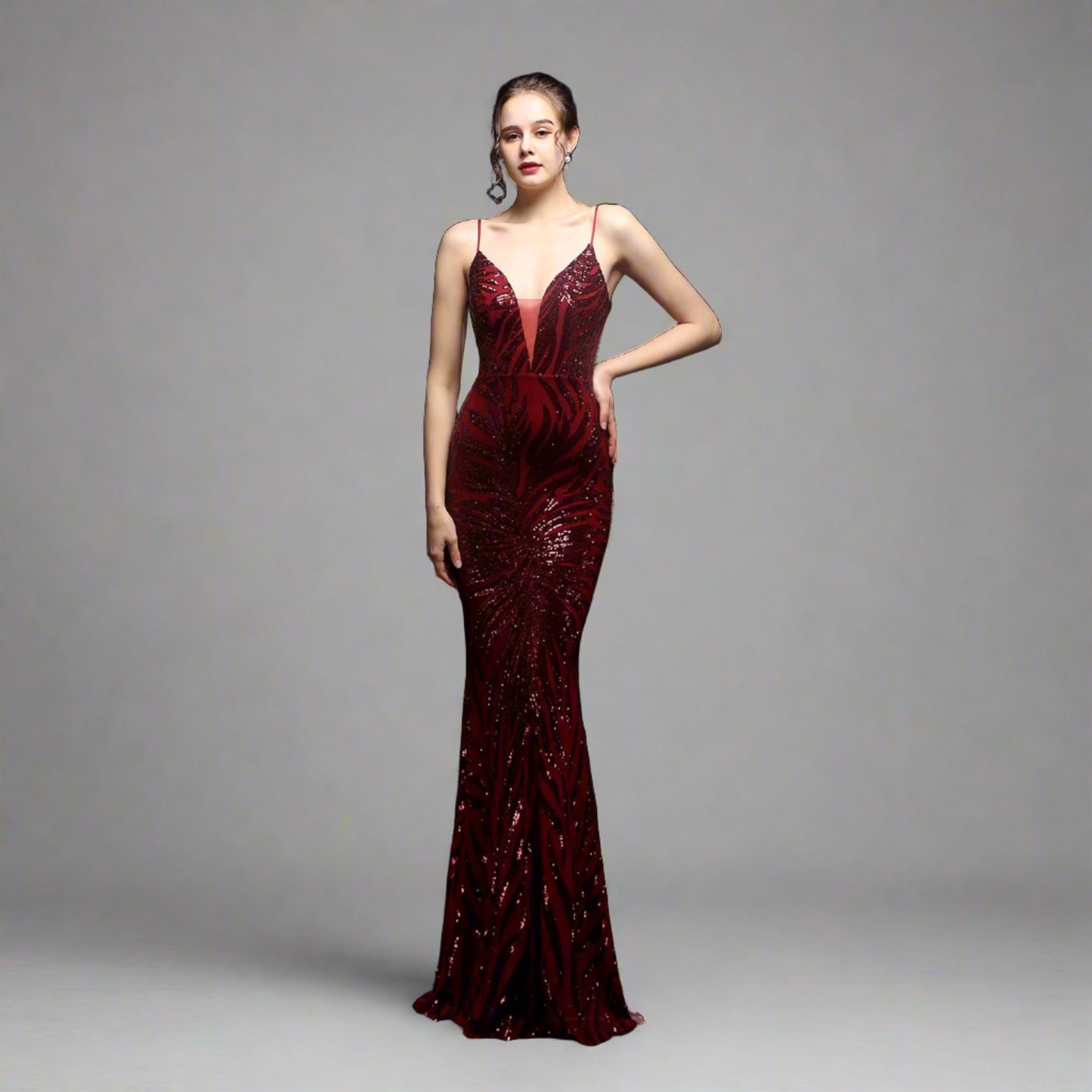 Model wearing Luxury Traveler's Sequin Gala Gown in maroon, featuring a body-hugging silhouette with intricate sequin details and spaghetti straps